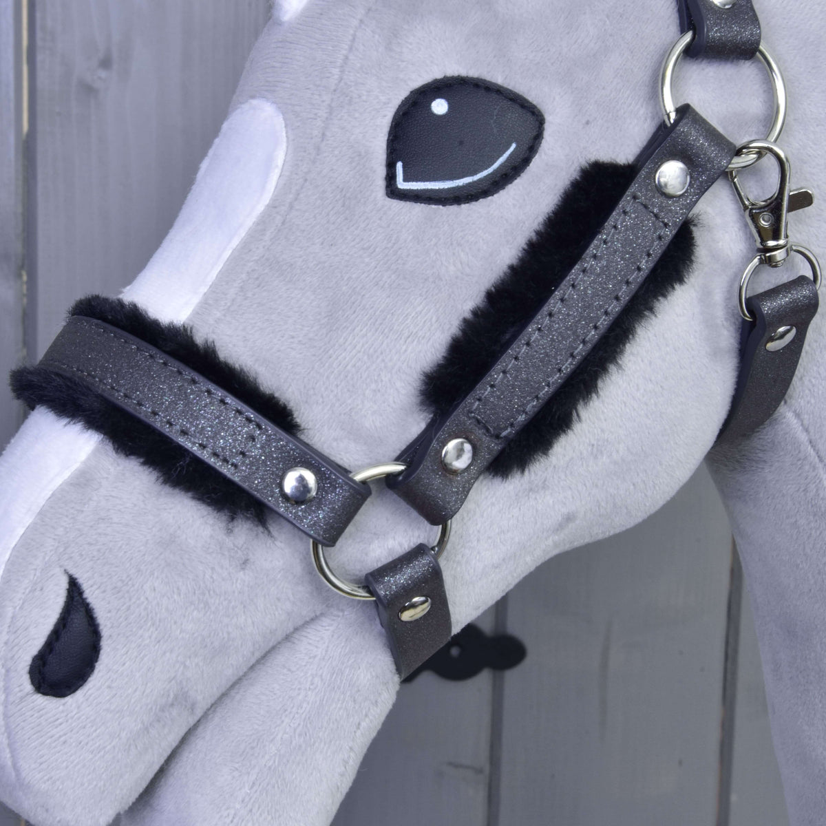 Close-up of the glittery graphite noseband and cheekpiece padded with black fur, with silver rings and snap hook
