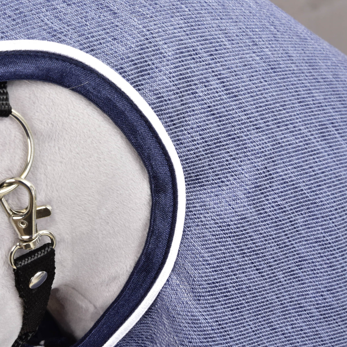 A Jeans esőtakaró közelről: farmer struktúrájú kék anyag sötétkék szegéllyel és fehér paszpóllal a nyaknyílásnál