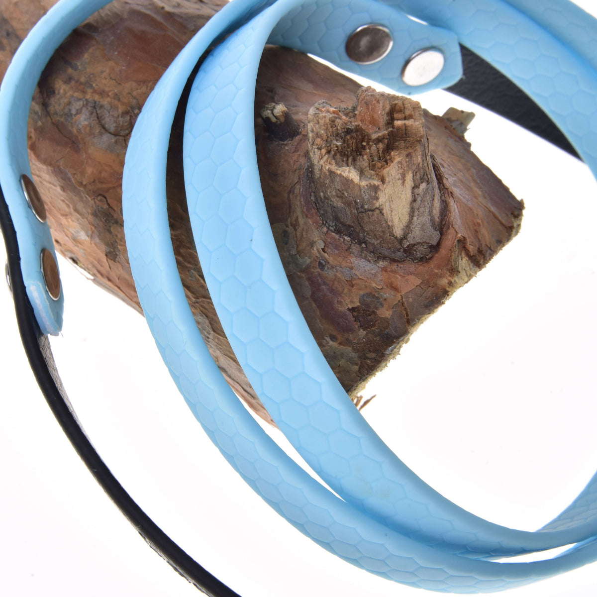 Világoskék gumírozott Hobby Horse kantárszár közelről méhsejtmintás felülettel és ezüst szegecsekkel, egy ág köré tekerve