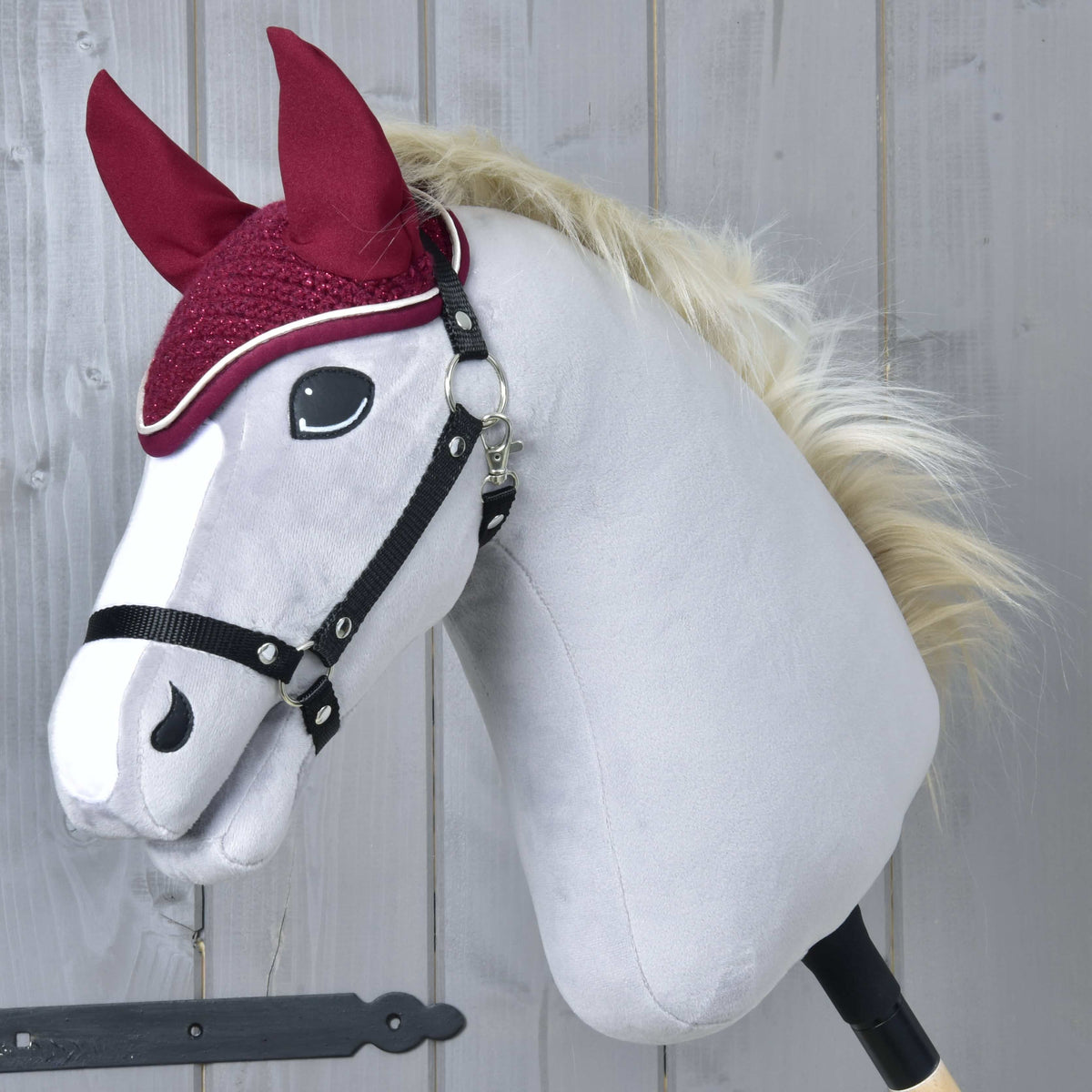 Szőke sörényű, szürke Hobby Horse ló fekete kötőfékben, a csillogó horgolt Lux Maroon fülvédővel
