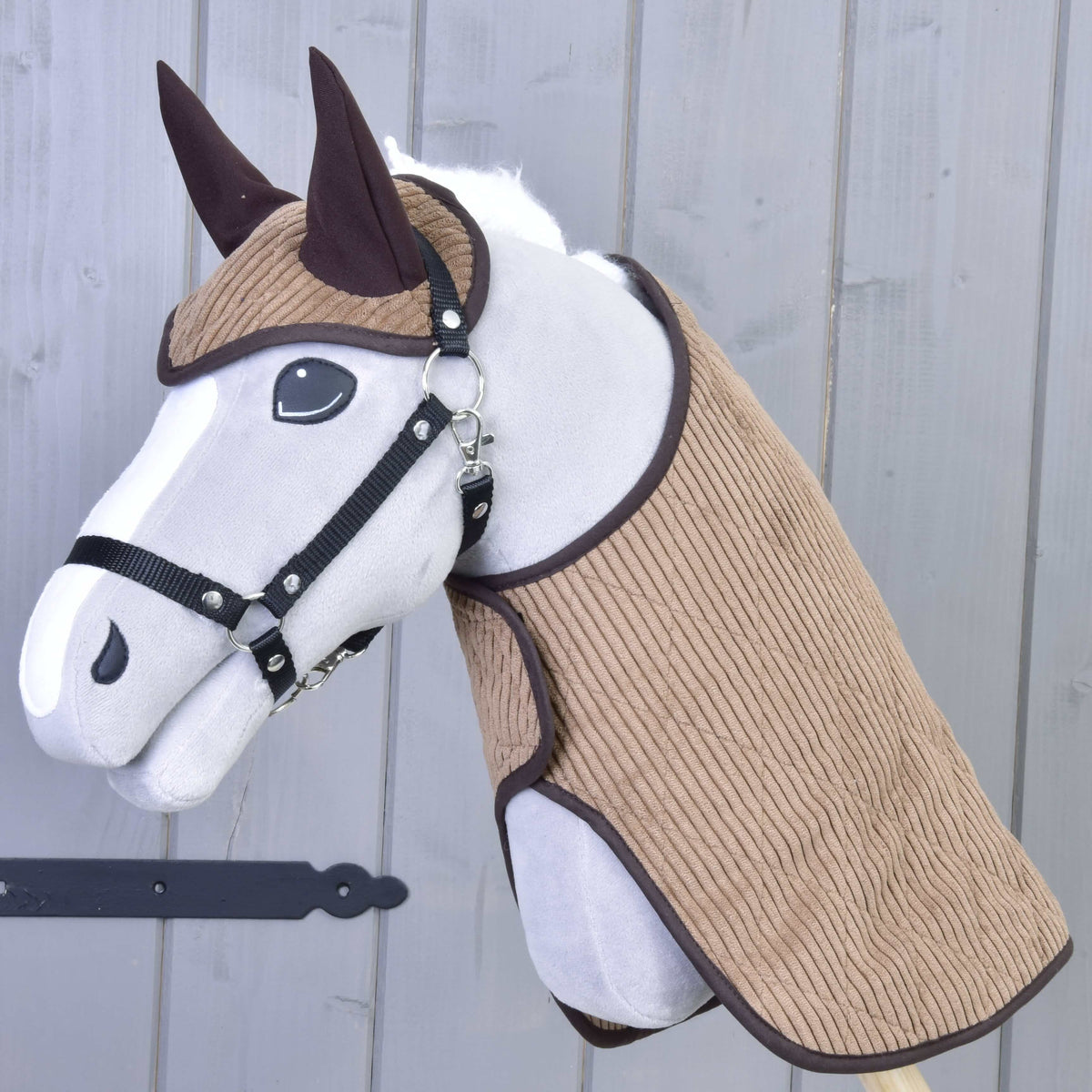 Fekete kötőfékes szürke Hobby Horse ló a világosbarna kordbársony takaróban és fülvédőben, sötétbarna szegéllyel
