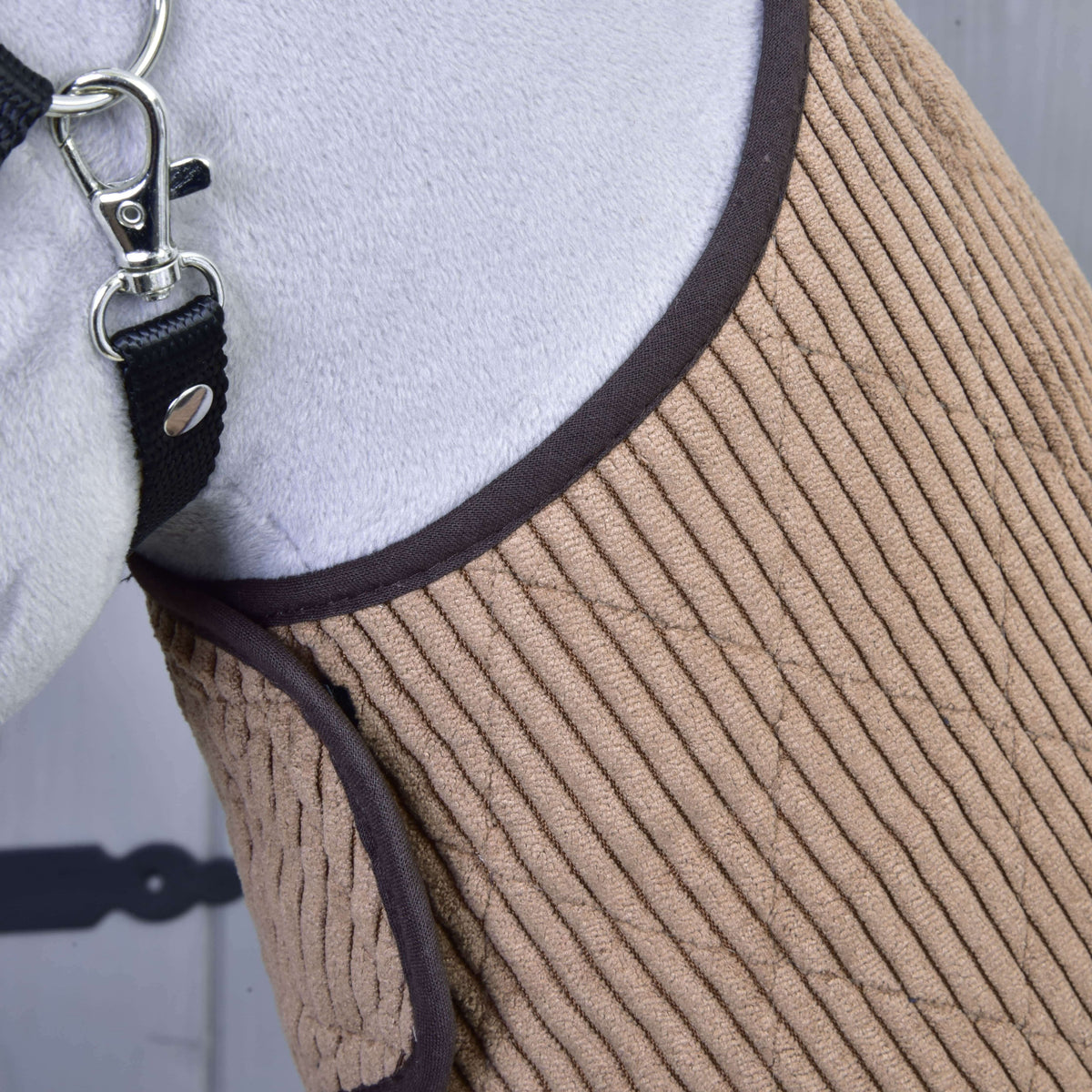 A bordázott kordbársony takaró közelről sötétbarna szegéllyel egy szürke Hobby Horse ló mellkasán