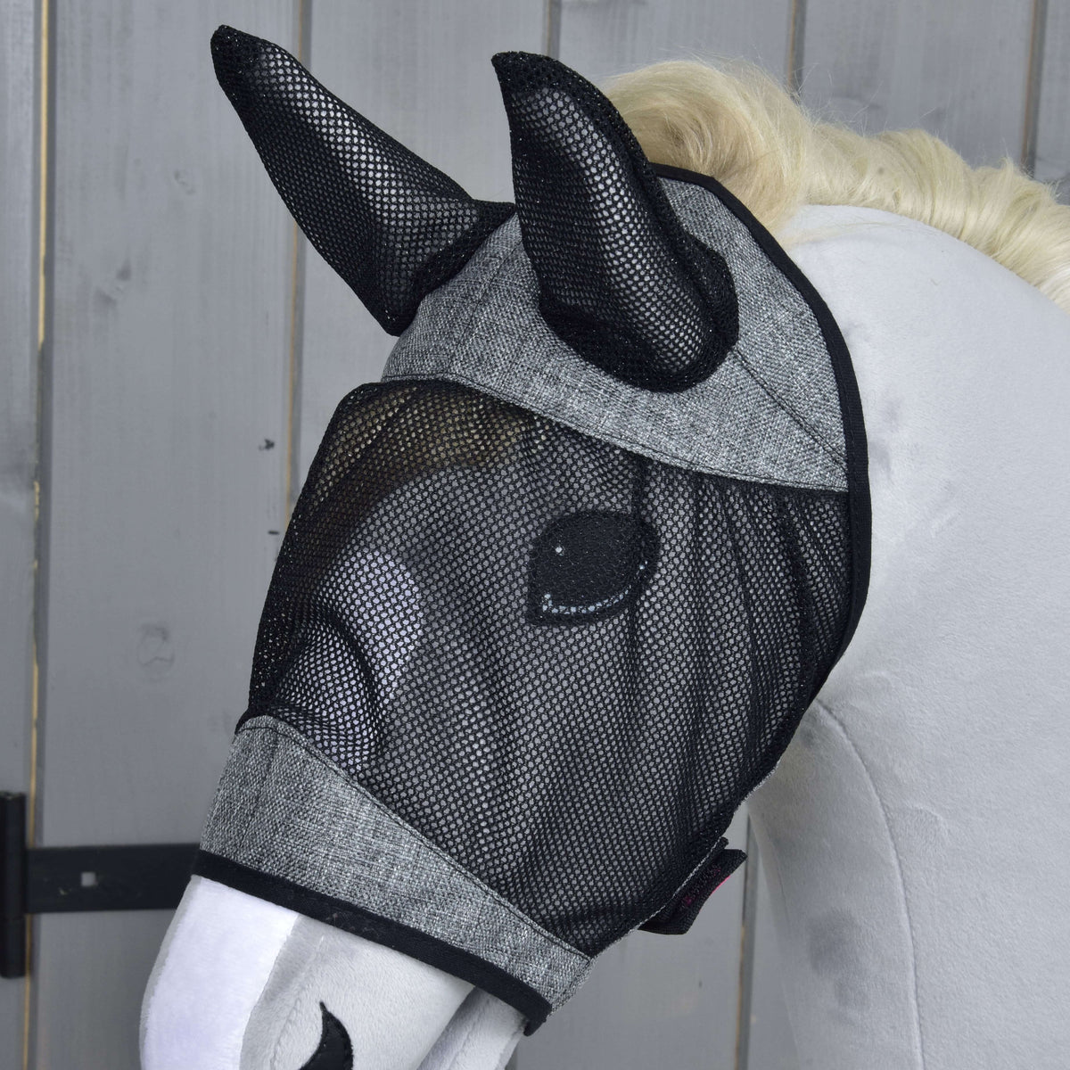 Close-up of the Fly Mask De Luxe Light Grey on a grey Hobby Horse, the black mesh covering the eye and both ears