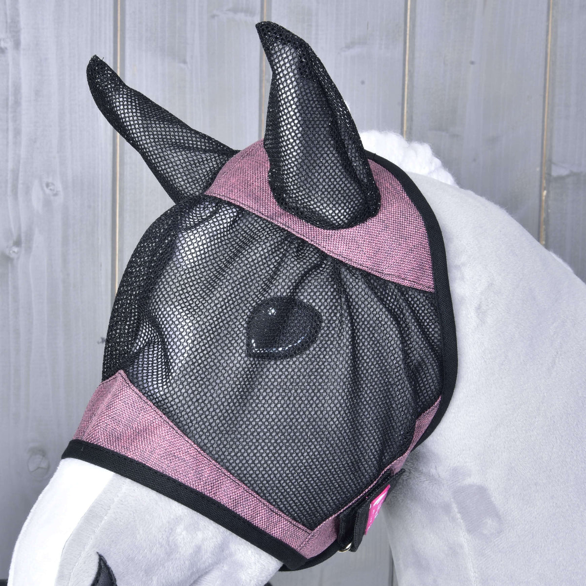 Close-up of the fly mask on a grey Hobby Horse from the side, black mesh over the eye and pink bands with black edging