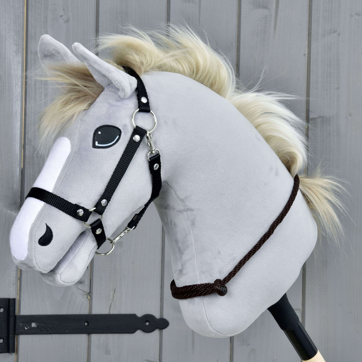 Krémszínű sörényű, világosszürke Hobby Horse ló fekete kötőfékben, a nyaka alsó részén a Chocolate nyakgyűrűvel (cordeo)