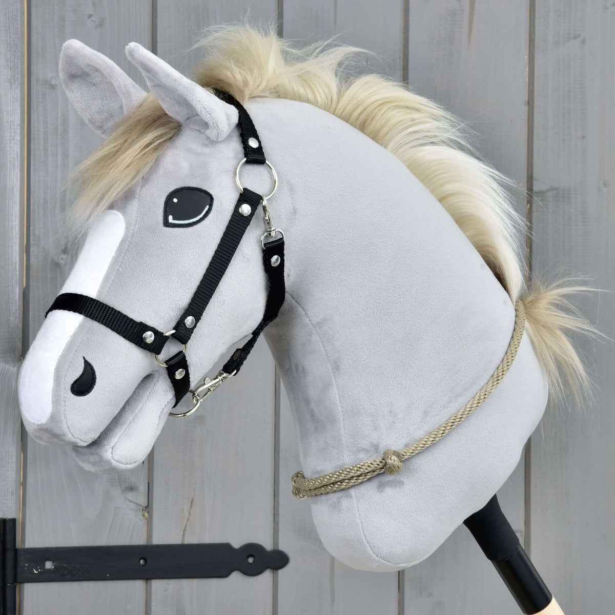 Light grey Hobby Horse in a black halter wearing the Cordeo Eleganza low on its neck, a beige-grey knotted rope