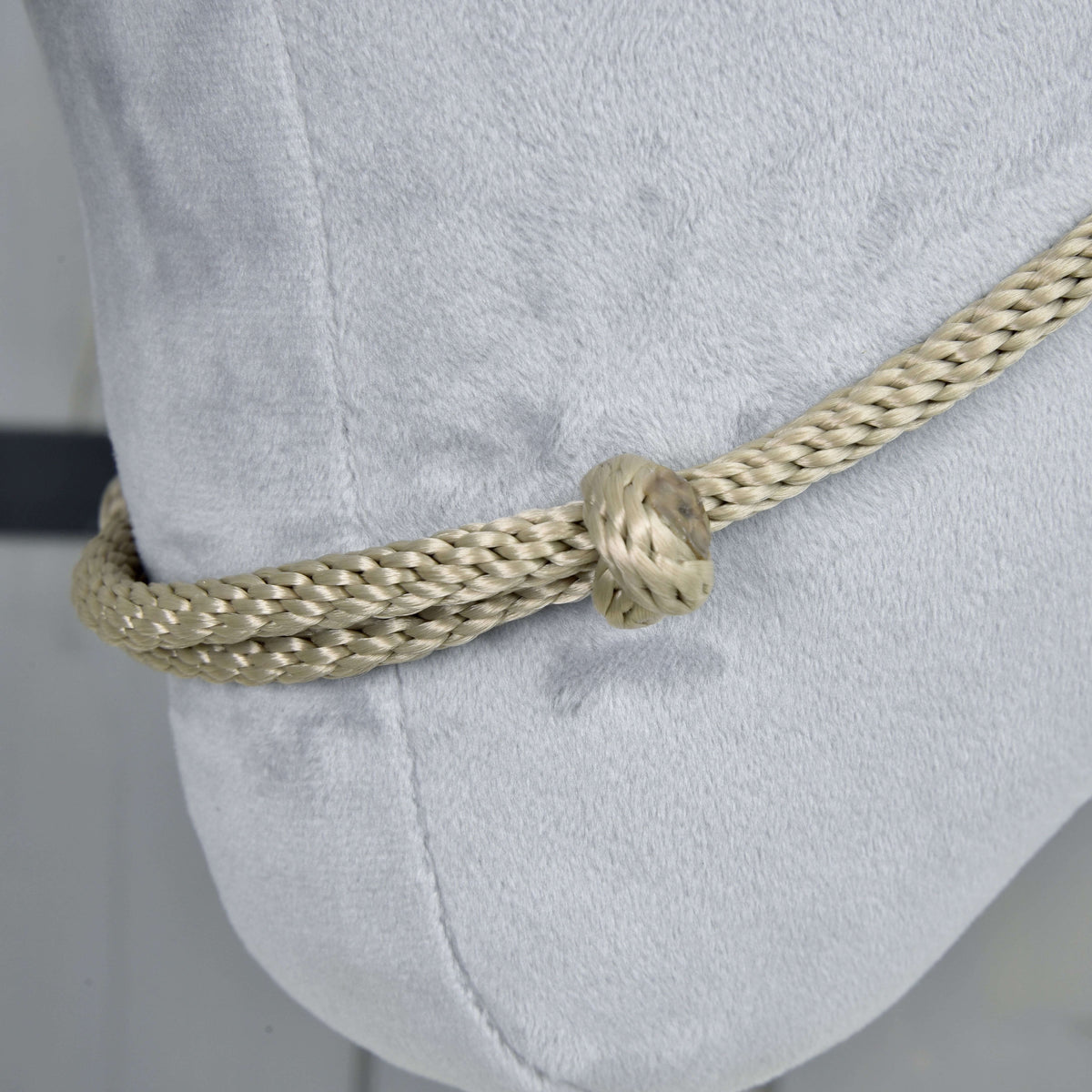 Close-up of the Cordeo Eleganza on light grey plush: braided beige-grey rope doubled through a round knot