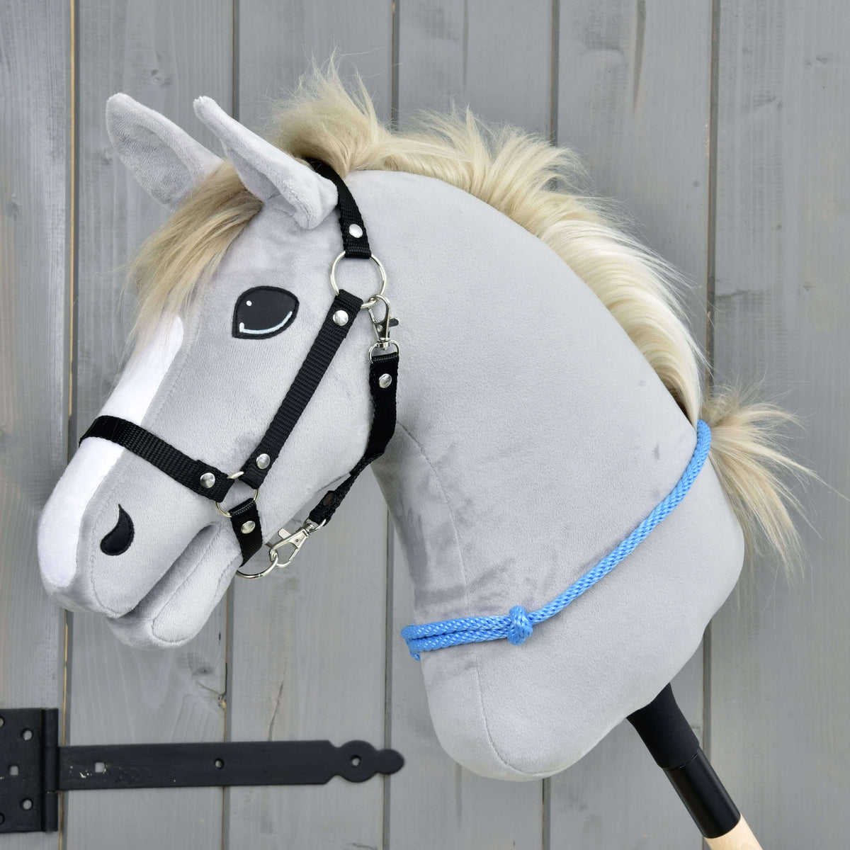 Light grey Hobby Horse with a cream mane and black halter wearing the Cordeo Sky, a blue knotted rope low on its neck