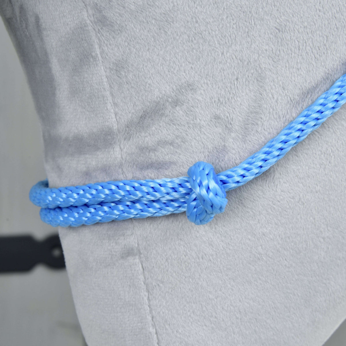 Close-up of the Cordeo Sky on light grey plush: bright blue braided rope doubled through a round knot