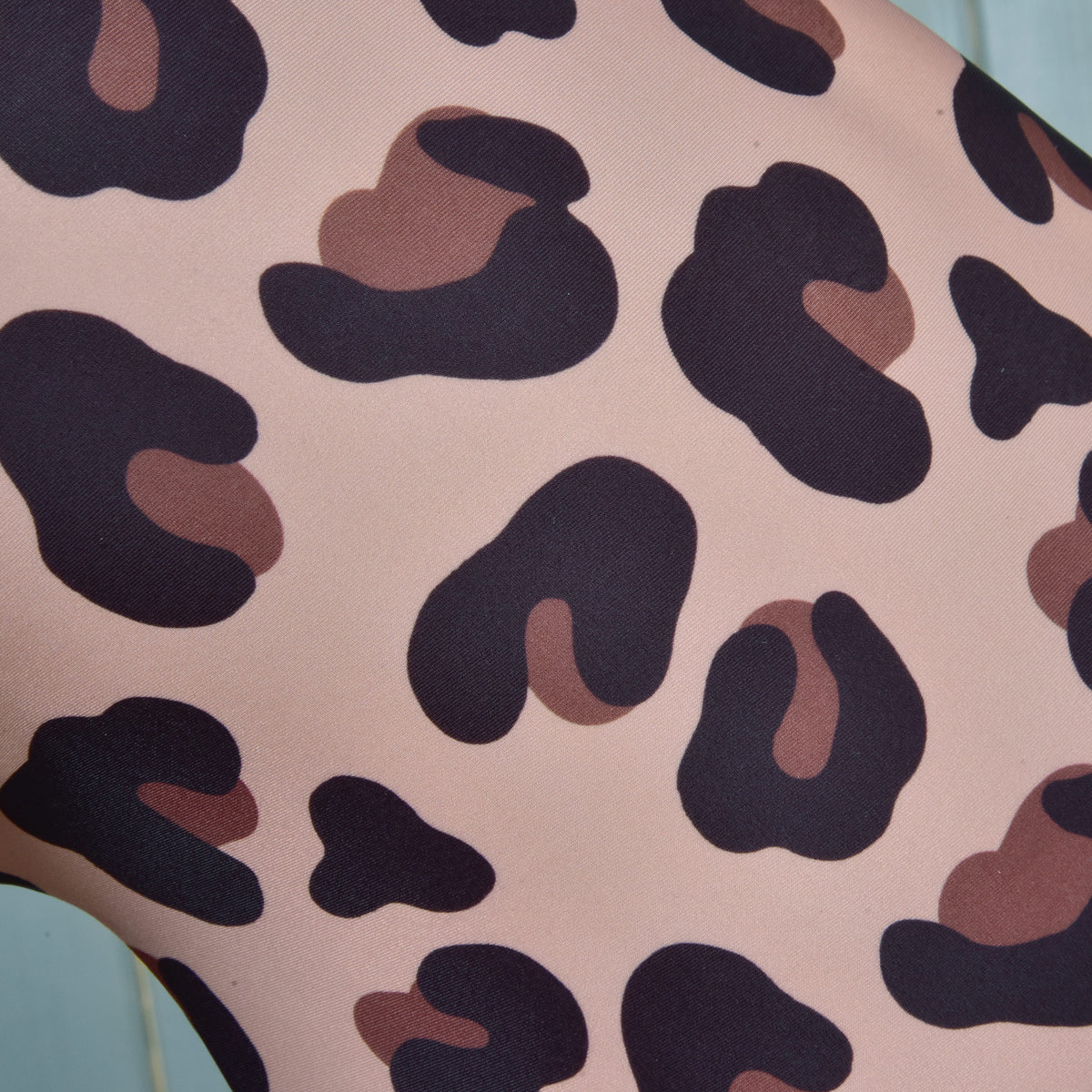 Close-up of the Glamour print: dark brown and rust leopard spots on smooth blush pink fabric