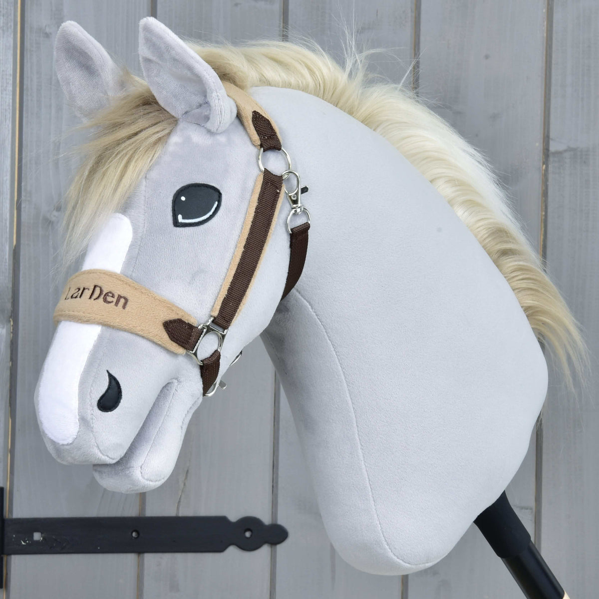 Szürke plüss Hobby Horse ló krémszínű sörénnyel a barna szőrmés kötőfékben, a bézs orrszíjon LarDen hímzéssel