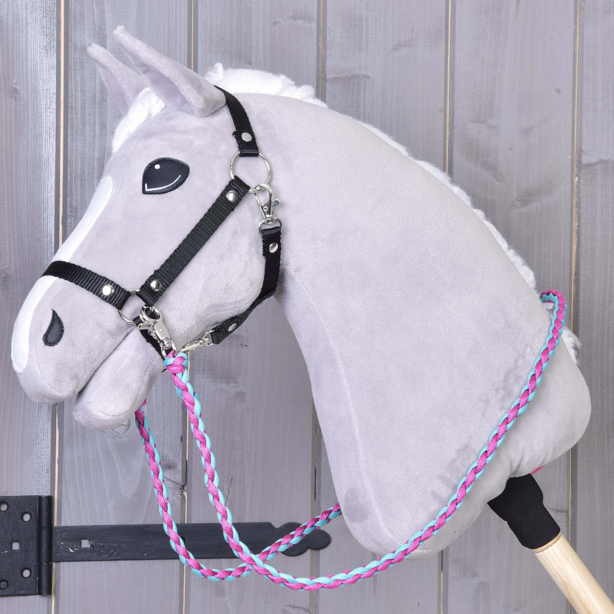 Grey plush Hobby Horse in a black halter with the Reins knitted pinkie blue clipped to the side rings