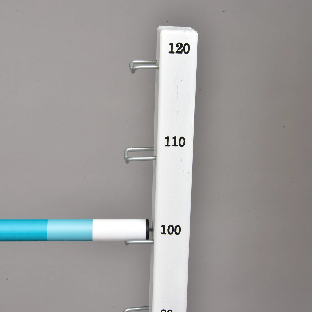 Turquoise and white pole resting on the metal hook at 100 cm on a white stand marked up to 120