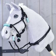 Szürke Hobby Horse ló a türkiz tekerésű fekete csomózott kötőfékben, a nyakán a hozzáillő fekete kantárszárral