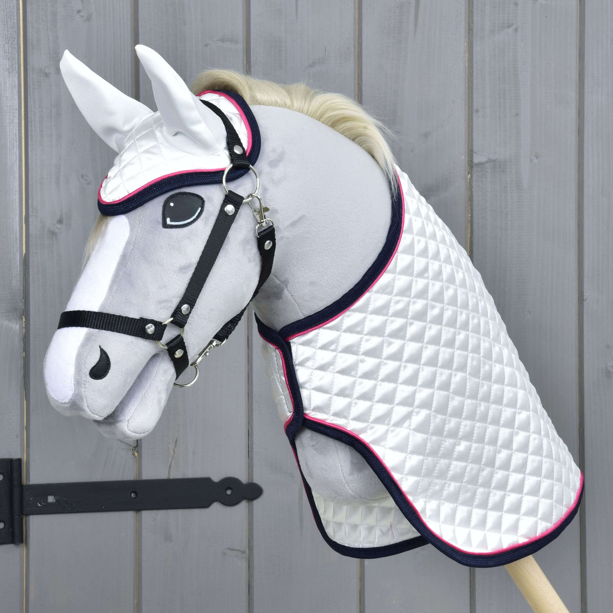 Szürke plüss Hobby Horse ló fekete kötőfékben, a fehér steppelt szaténtakaróban és fülvédőben, sötétkék és rózsaszín díszítéssel