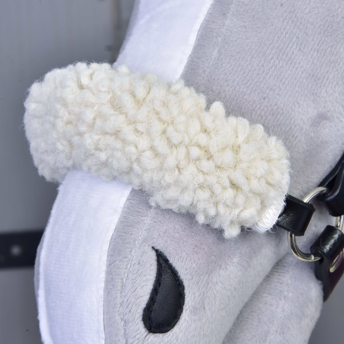 A Harmony Elsa szett kötőfékének krémszínű, göndör polár orrszíjpárnája közelről egy szürke Hobby Horse lovon