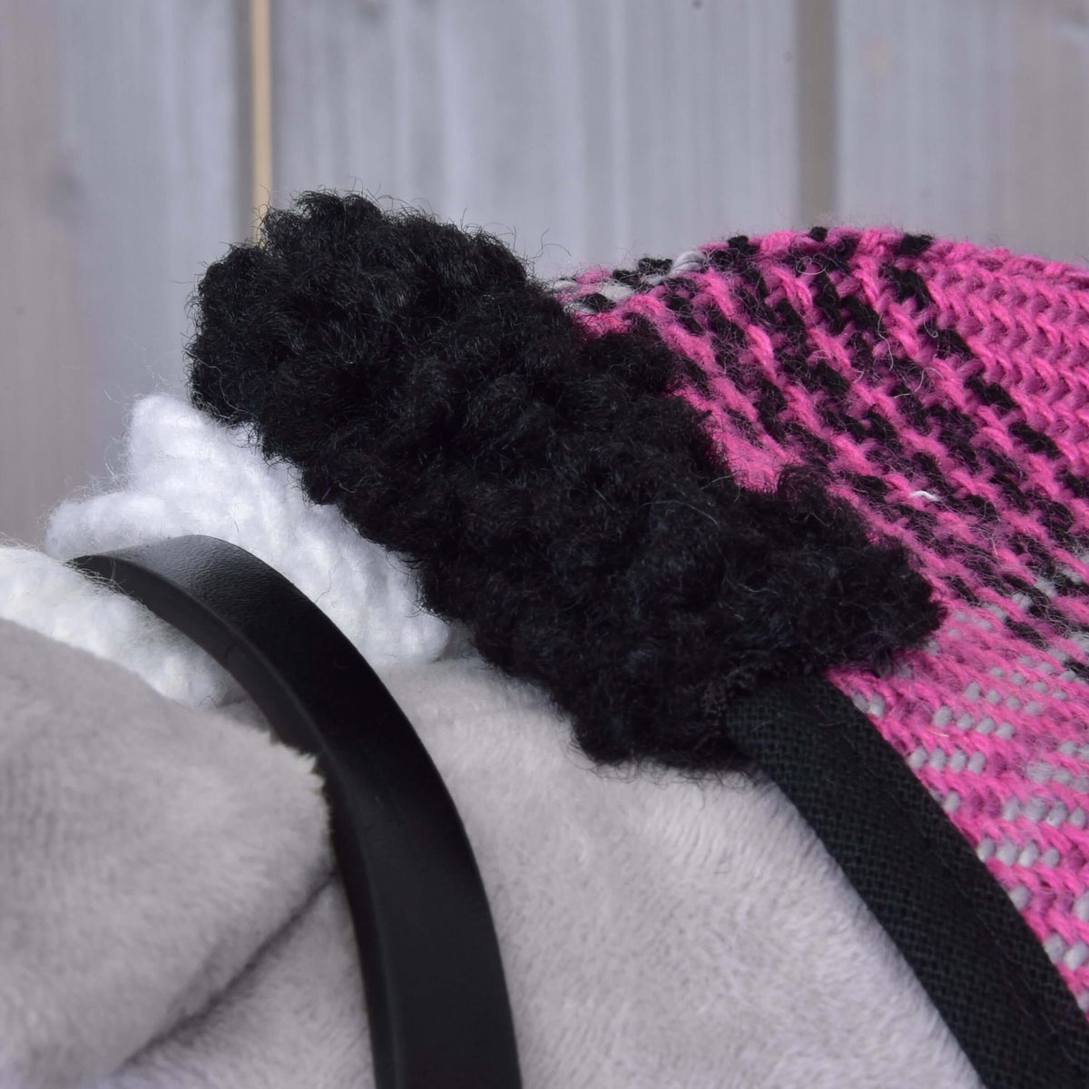 A fekete, göndör polárgallér közelről a Harmony Pink szett rózsaszín-fekete kockás takaróján egy Hobby Horse lovon