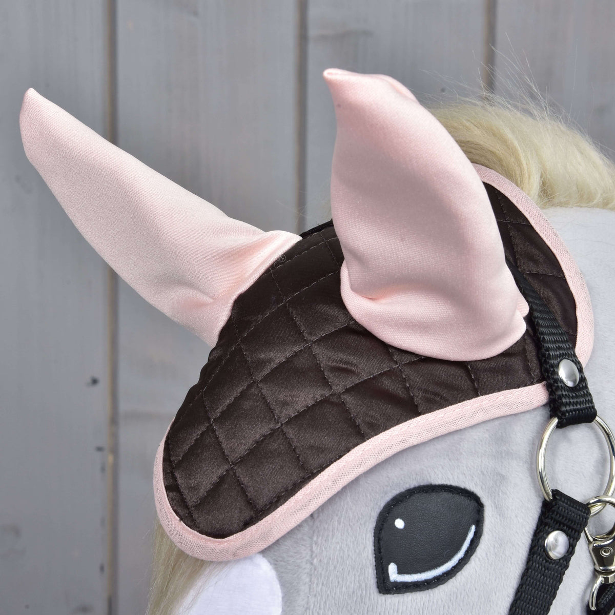 Set Thermo Sweety ear bonnet on a grey Hobby Horse in a black halter, close-up of the light pink ears and pink edge