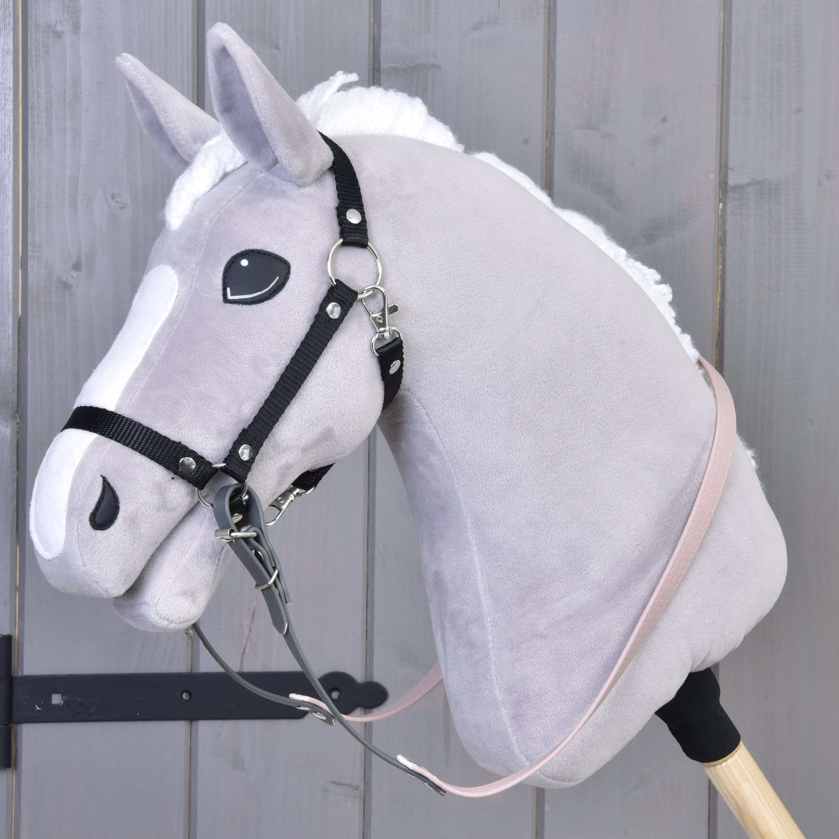 Szürke plüss Hobby Horse ló fekete kötőfékkel és a karikáihoz csatolt gumírozott sötétszürke-halvány rózsaszín kantárszárral