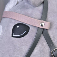 A halvány rózsaszín, mintázott homlokszíj közelről ezüst szegeccsel a szürke műbőr kantáron, a Hobby Horse ló szeme mellett