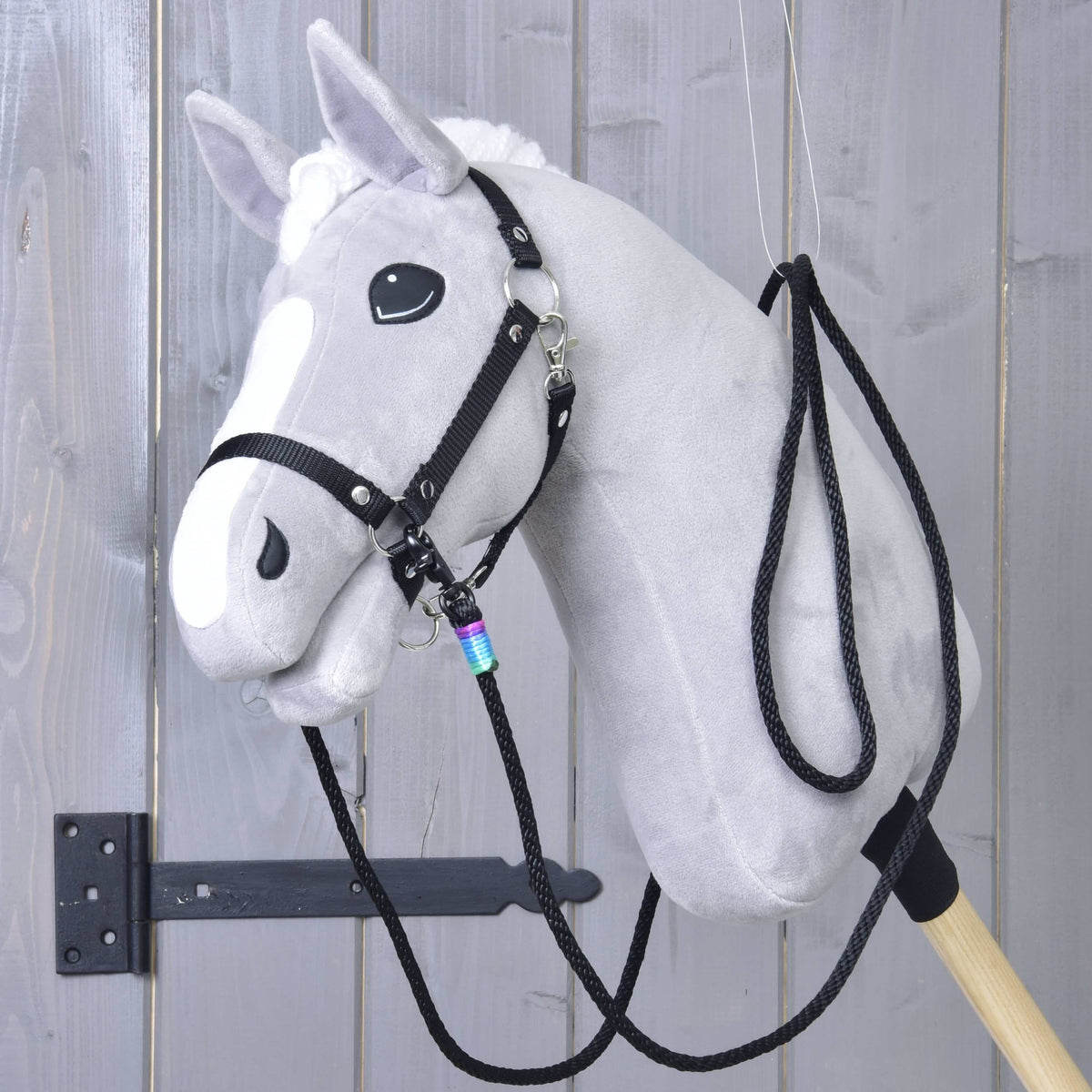 Szürke Hobby Horse ló fekete kötőfékben, a fekete western kantárszár mindkét oldalon bekapcsolva és a nyakára vetve