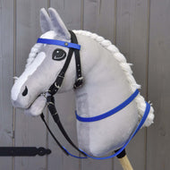 Szürke plüss Hobby Horse ló fekete kantárban kék homlokszíjjal és a kék gumírozott kantárszárral, háttérben szürke fafal