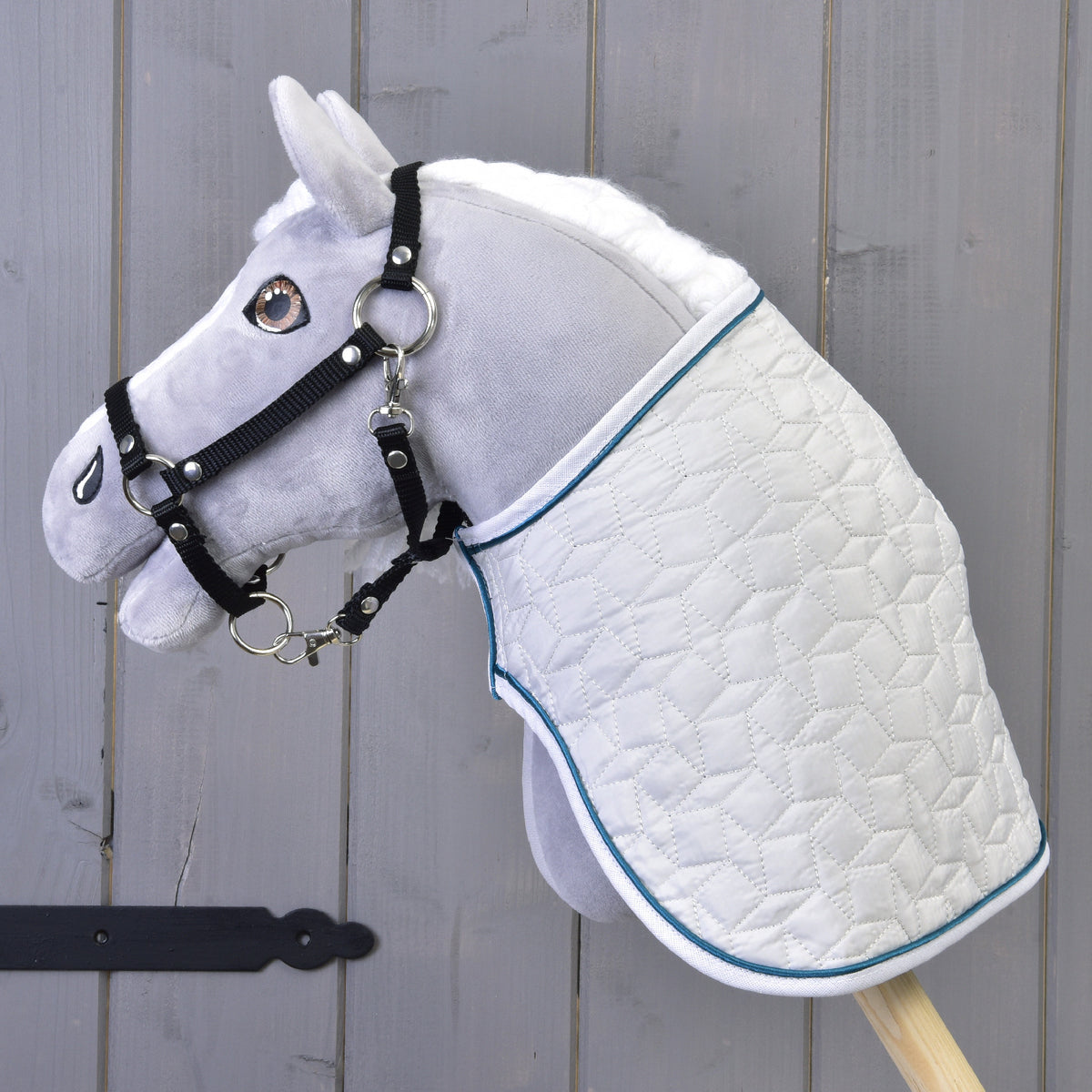 Fehér sörényű, fekete kötőfékes szürke Hobby Horse ló bal profilból, a fehér steppelt Thermo Pearl takaróban