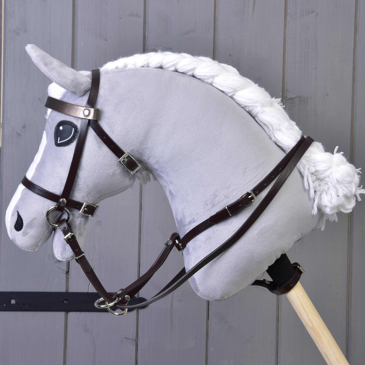 Grey plush Hobby Horse with a braided white mane in a dark brown bridle, reins and the brown martingale
